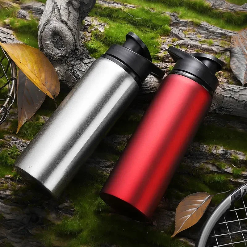 Silver and red AZNOLT gym water bottles on mossy wood with tennis racket and autumn leaves